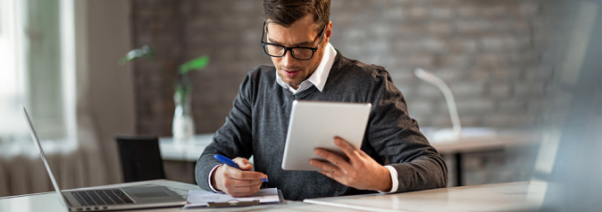 Businessman writing financial reports and using digital tablet in the office