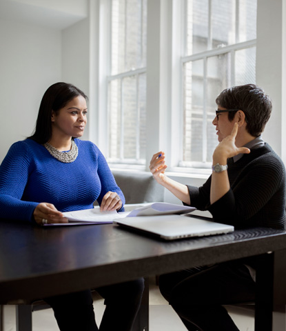 female colleagues discussing while sitting at desk