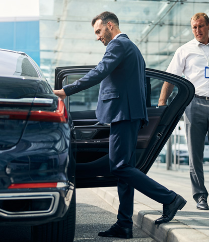 man in a nice suit opening a car to begin commute from the airport